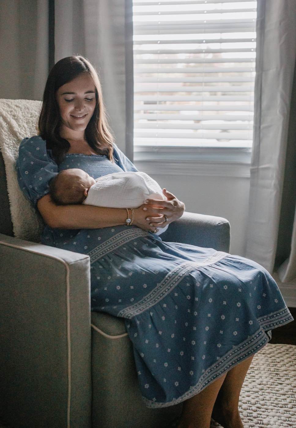 Softly lit portrait of a mother cradling her newborn baby in a serene, intimate setting.
