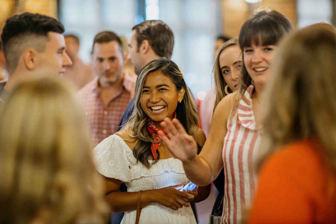 Joyful group of young adults interacting at an indoor event with warm lighting.