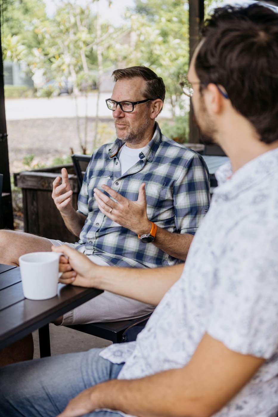 Two men in casual attire having an outdoor conversation, natural light, relaxed mood.