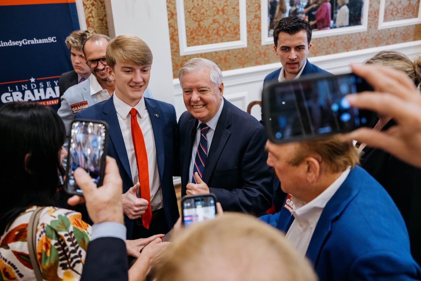 Brightly lit indoor event with a joyful mood, people interacting and taking photos.
