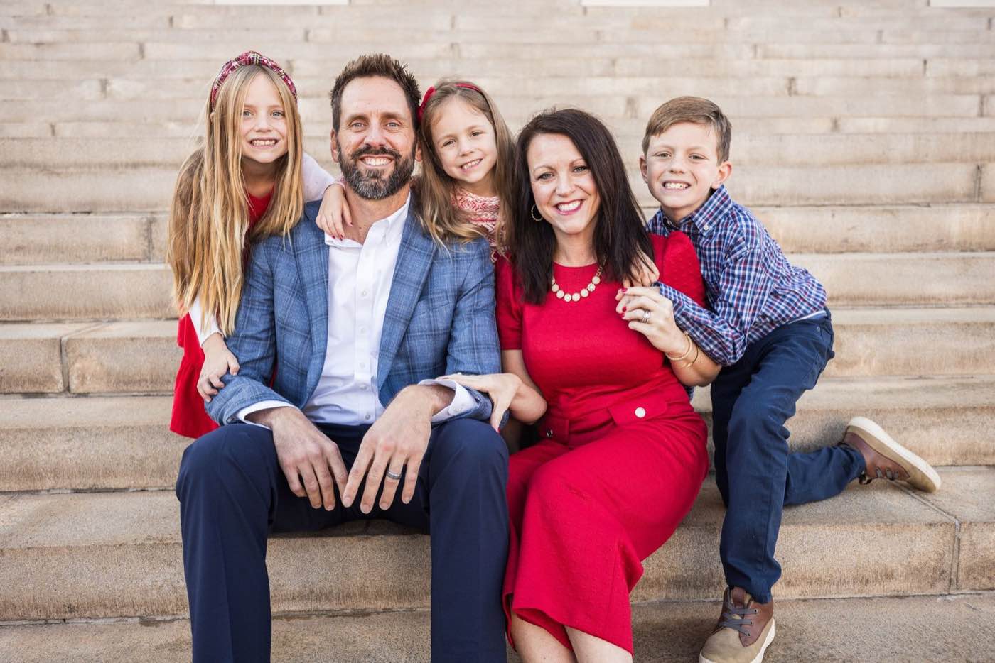 Joyful family of five sitting on stone steps, bathed in warm, natural light.